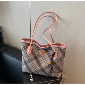 Detail der Tweed-Einkaufstasche mit rosa Lederbesatz und dreieckigem Logo vor dunklem Hintergrund