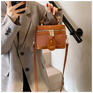 Detail view of a vintage brown leather bucket bag styled with a grey tailored blazer