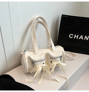 Détail du sac cylindrique crème brillant avec des nœuds en ruban et poches zippées