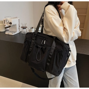 Detail of black nylon bucket bag with multiple pockets and wide strap in a cafe