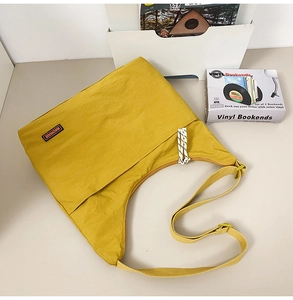 Detail view of yellow nylon crossbody bag with MACHUGE brand label and adjustable strap
