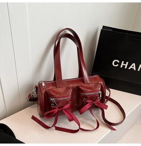 Détail du sac cylindre bordeaux avec nœuds décoratifs et doubles poches zippées devant