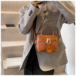 Close-up of vintage brown leather bucket bag held by model on urban stairs context