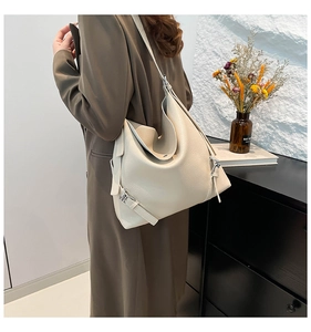 Detailed view of beige pebbled leather tote bag with wide strap and silver buckle detail