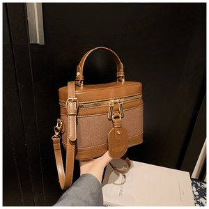 Detail of vintage canvas bucket bag with brown leather trim and dual gold zippers