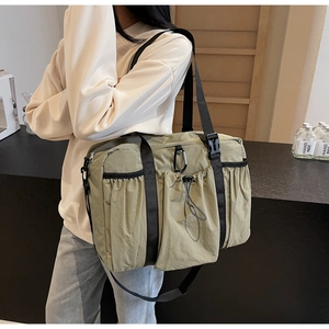 Detail of olive green nylon crossbody bucket bag with functional pockets and carabiner