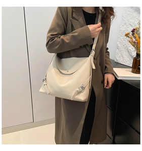 Detail of adjustable shoulder strap and silver buckle on a beige leather tote bag