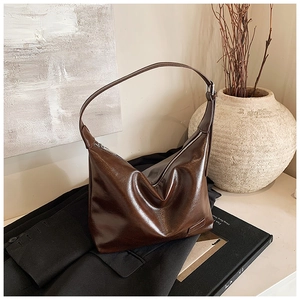 Detailed close-up of dark brown vintage faux leather shoulder bag on a black blazer