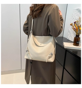 Close-up of cream shoulder bag featuring pebbled leather texture and adjustable side buckles