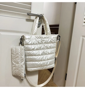 Detail of white quilted puffer tote bag with a small matching pouch and wide shoulder strap