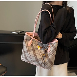 Braune Karo-Tragetasche mit rosa Ledergriffen und goldenem Logo an einem Modell