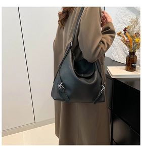 Close-up of black lychee grain leather tote bag featuring side silver buckle details