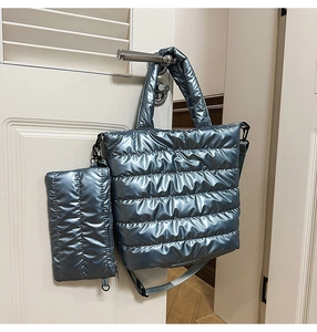 Detail of metallic blue quilted tote bag and matching pouch on a door handle