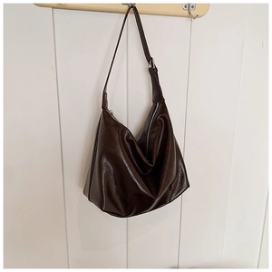 Detailed close-up of a dark brown glossy PU leather hobo bag with elegant folds