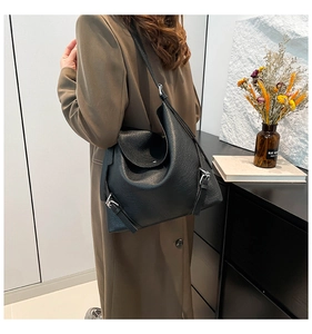 Side view of black lychee grain leather tote bag with silver buckle on a model