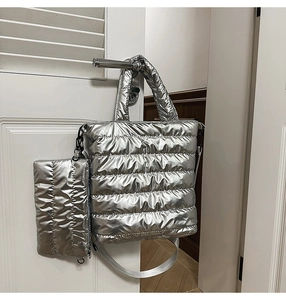 Silver quilted tote bag set with matching small pouch and wide strap on white door