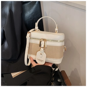 Detail of box-shaped bucket bag with two-way gold zippers and woven fabric texture