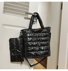 Close-up of black quilted puffer tote bag with matching zipper pouch and strap