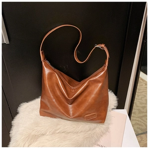 Close-up of a large dark brown faux leather hobo bag with glossy finish and logo tag