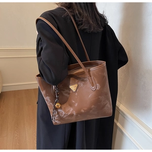 Detailansicht braune Leder-Einkaufstasche mit Metallplakette und Glockenanhänger