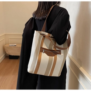 Detailed view of canvas tote bag with striped pattern and leather zipper pocket