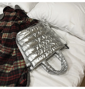 Close-up of silver quilted puffer tote bag with metallic finish and long strap