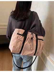 Pink oversized nylon bucket bag with black adjustable straps shown on a model