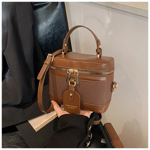 Close-up of vintage brown leather bucket bag with textured fabric and gold zipper