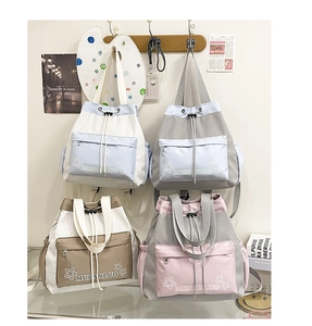 Detail of four canvas bucket backpacks in low-saturation tones with drawstring and star print