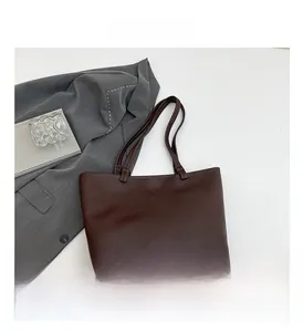 Detail view of dark brown faux leather tote bag with lychee texture and long strap