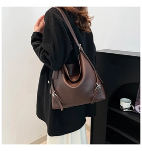 Detail of dark brown leather tote featuring lychee texture and silver buckle accents