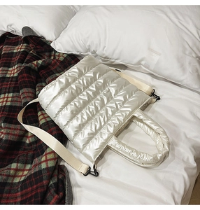 Detail of white quilted puffer tote bag with glossy finish and detachable nylon strap