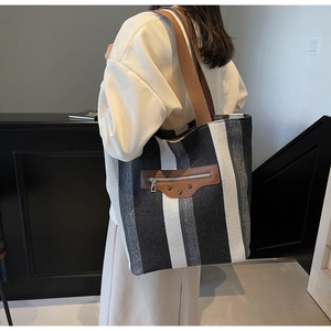 Detailed back view of striped canvas tote bag with brown straps and rivet pocket