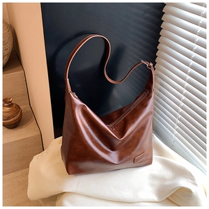 Detail of caramel leather shoulder bag showing glossy texture and silver buckle
