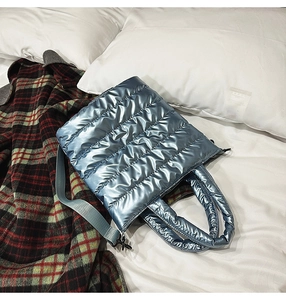 Detail of blue metallic quilted tote bag with padded texture and wide shoulder strap