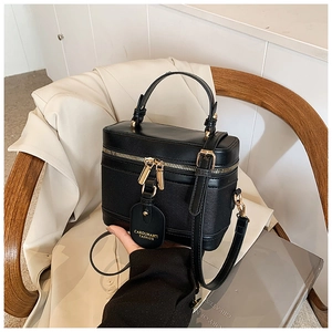 Detail of black textured bucket bag with gold zippers and detachable shoulder strap