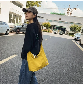Detail of yellow canvas crossbody bag featuring dual slanted zipper pockets for commute
