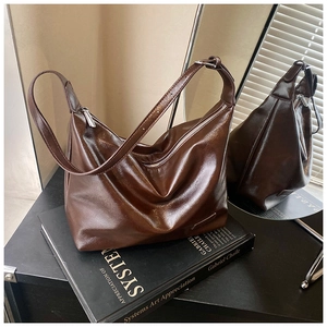 Detail of dark brown glossy leather tote bag with silver zipper on artistic books