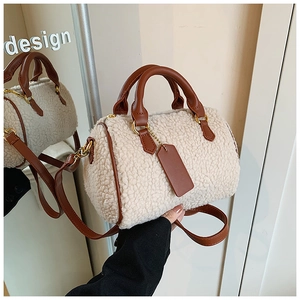 Close-up of cream fuzzy boston bag with brown leather handles and gold hardware details
