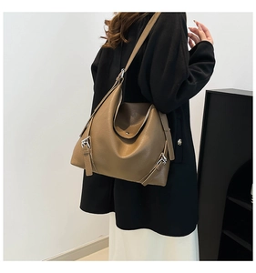 Detail of hobo bag in brown lychee grain leather with metallic buckle side strap