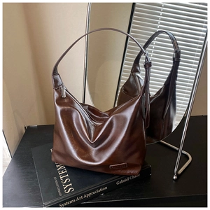 Detail of glossy brown oversized hobo bag showing metallic zipper and smooth leather texture