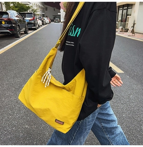 Detail of yellow canvas crossbody bag with adjustable strap and MACHUGE label