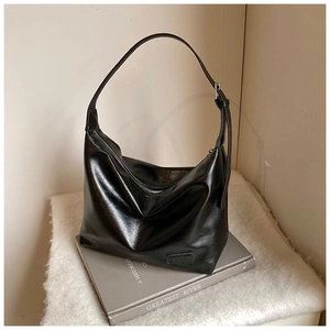 Detail of a black shiny leather hobo bag on books with focus on texture and logo