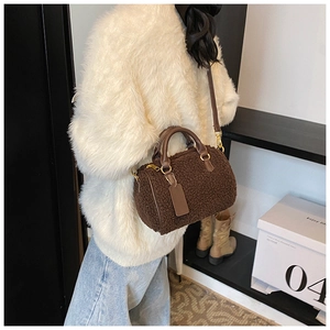 Detail view of brown plush Boston bag with leather handles and gold-tone hardware