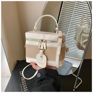 Detail of a vintage-style bucket bag with cream and khaki woven texture and gold hardware