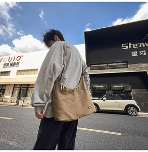 Street style view of a khaki canvas crossbody bag with drawstring detail and large capacity
