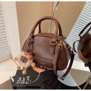 Close-up of brown vintage shell bag with gold lettering and plush animal keychain detail