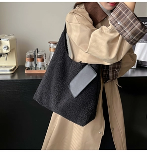 Detail of black faux shearling tote bag with leather pouch accessory and plush texture