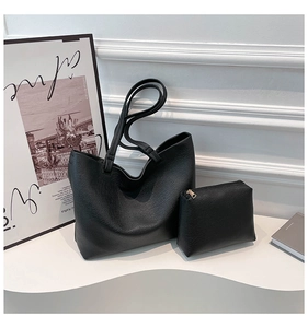 Detail of black lychee grain tote bag with matching zipper pouch on minimalist display