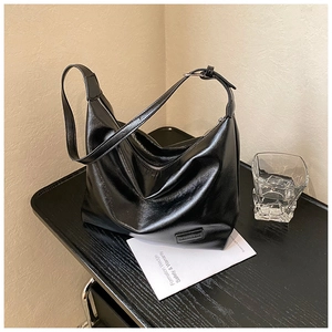 Detail view of black glossy hobo bag with a soft leather texture and zipper closure